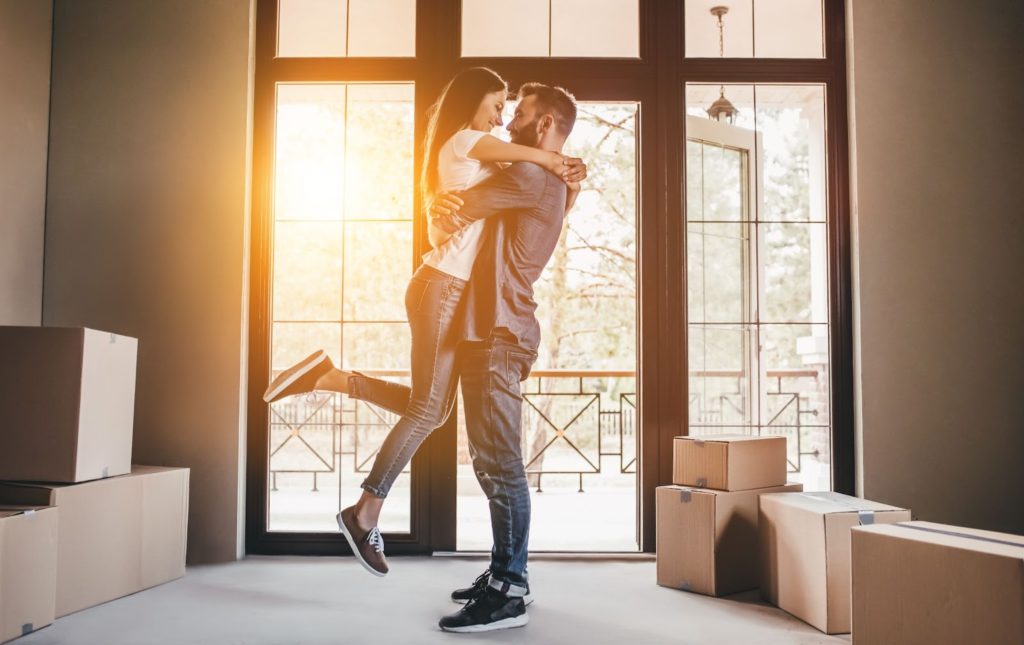 A happy couple hugging in the sun after moving into a home.