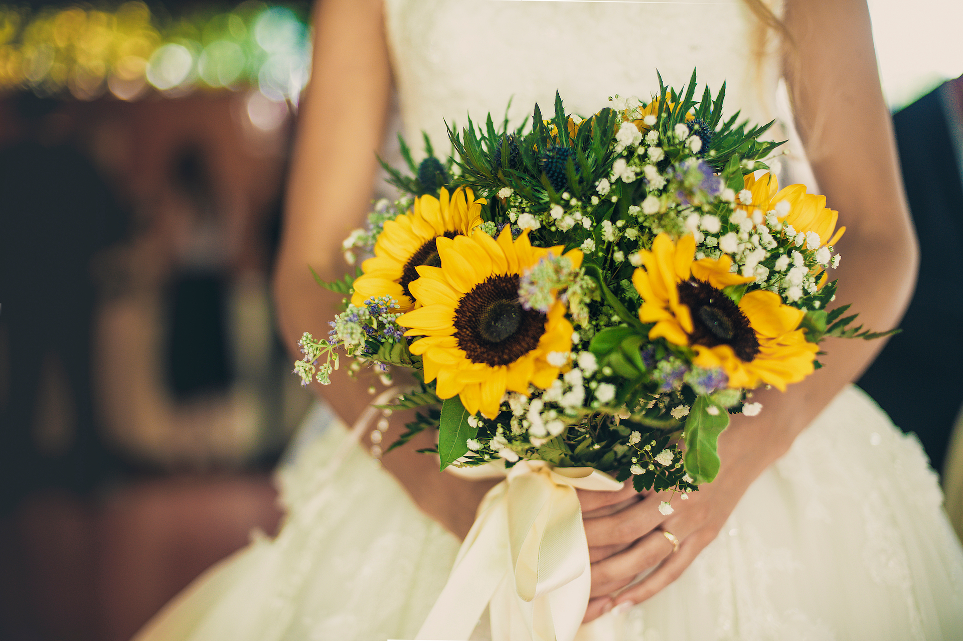 bride holding a cheerful wedding bouquet with sunflowers and greenery